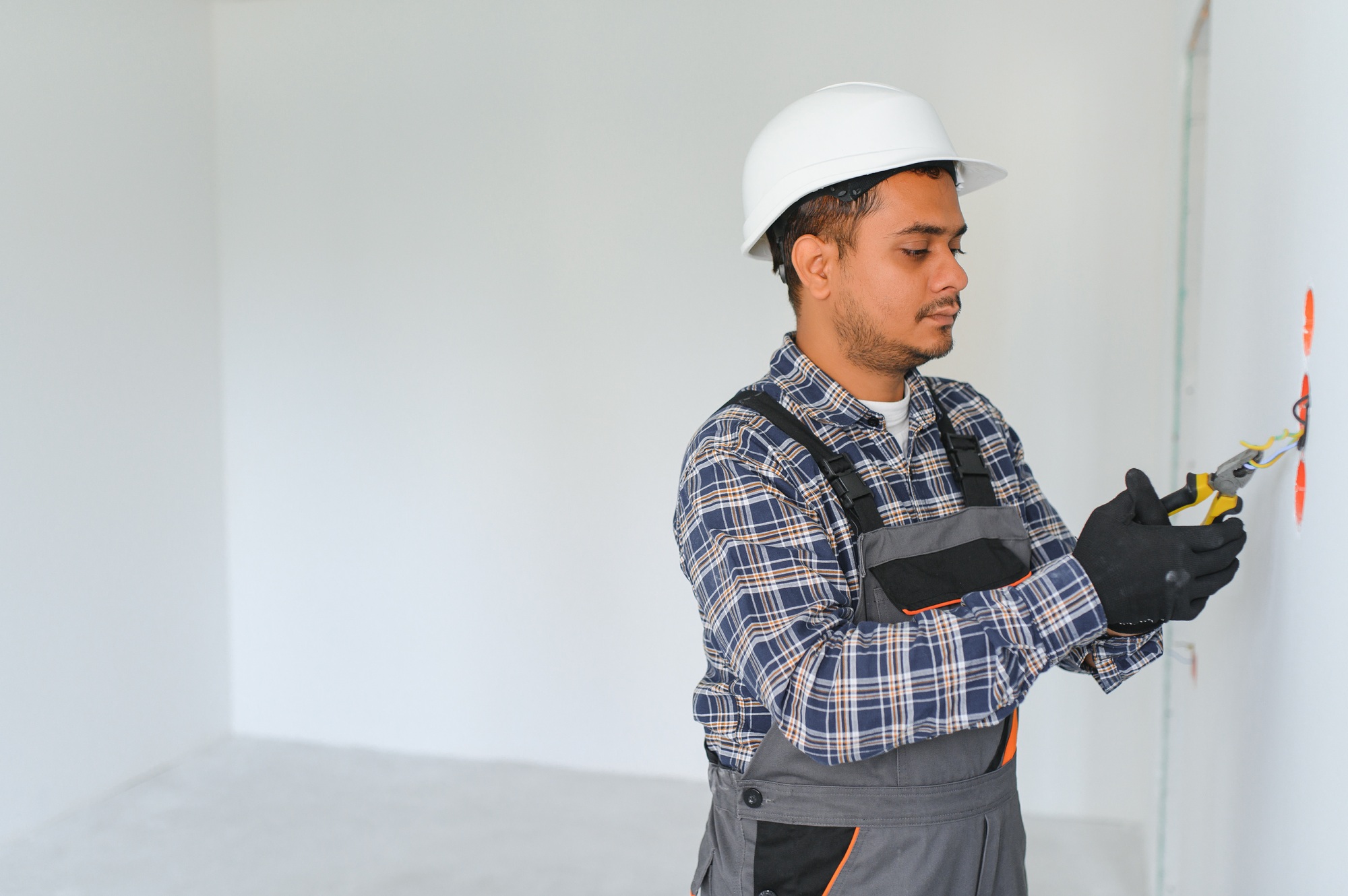 an Indian electrician installs an outlet in a new building